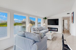 Relax in this stylish living room with a sofa, coffee table, and flat-screen TV, offering a view of the surrounding water and buildings.
