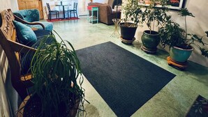 Una sala de estar acogedora con vigas de madera, chimenea, zona de comedor y varias plantas en macetas.