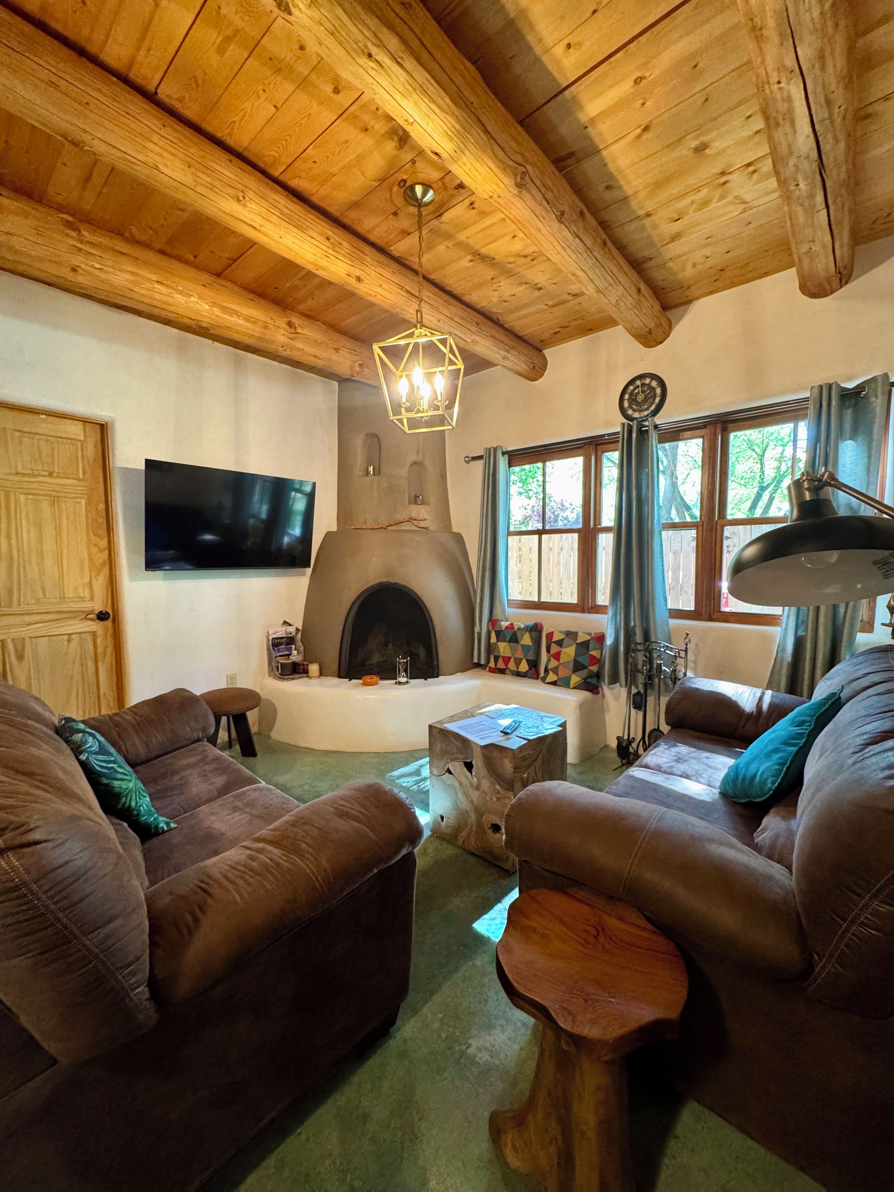 A rustic living room with a fireplace, wooden ceiling beams, and leather sofas.