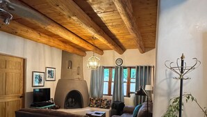 Una sala de estar acogedora con chimenea, vigas de madera en el techo, televisor y asientos cómodos.