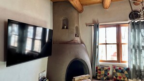 Una sala de estar acogedora con chimenea de piedra, un televisor montado en la pared y un ventanal con cortinas.