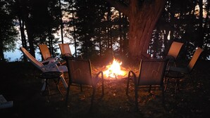 A campfire with four chairs arranged around it in a forest setting. - Charming and Cozy, 4-Season, Fence Lake Cottage with Beautiful Sunset View (Lac du Flambeau)