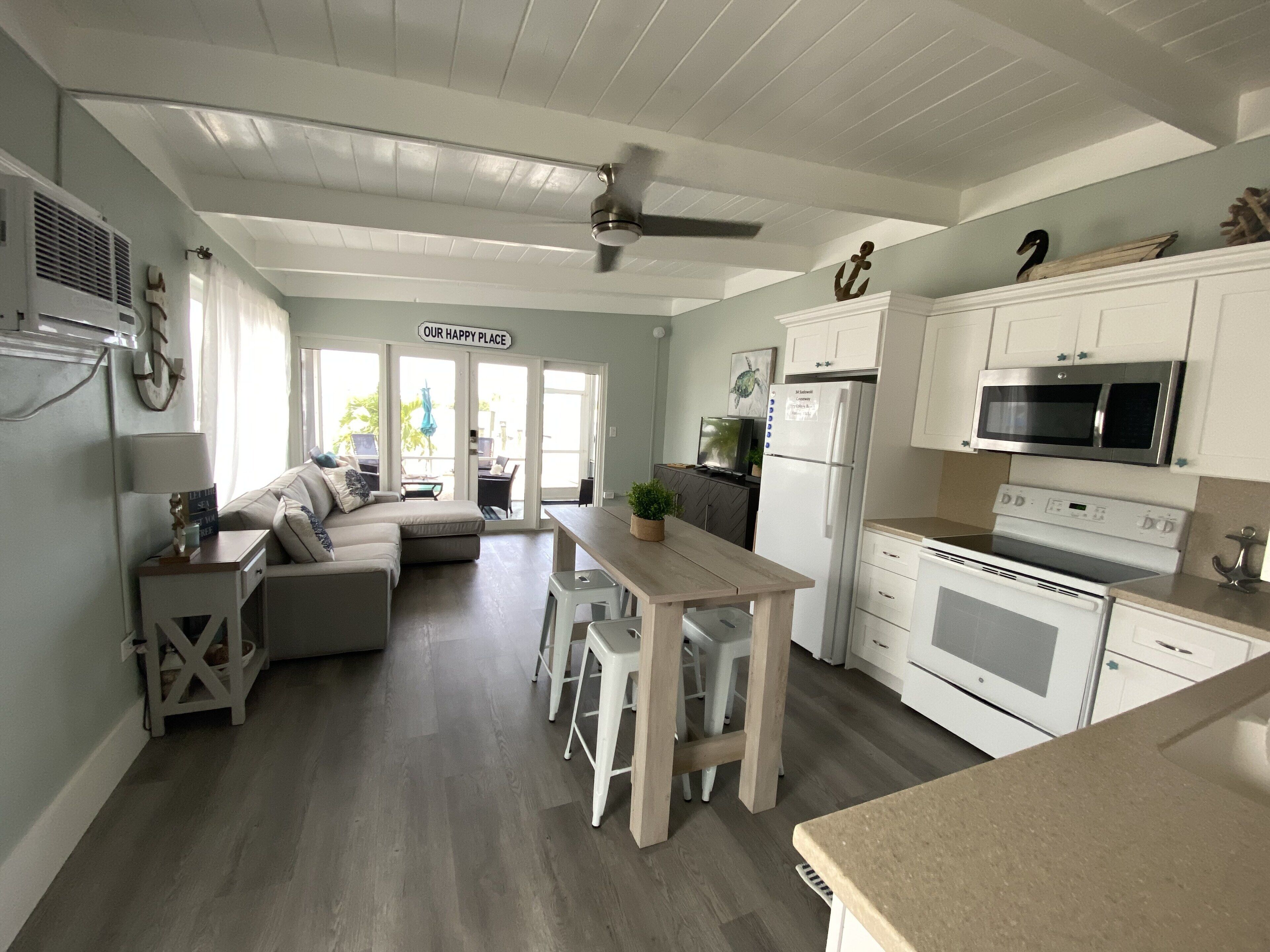 A modern kitchen with white cabinetry, a central island, and a dining area.