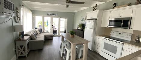 A modern kitchen with white cabinetry, a central island, and a dining area.