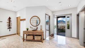 A modern interior with a wooden console table, a round mirror, and a decorative wall piece. - Bliss By the Bay (Brentwood Bay)