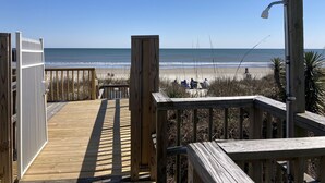 Ein Holzsteg führt zu einem Strand mit freiem Blick auf den Ozean.
