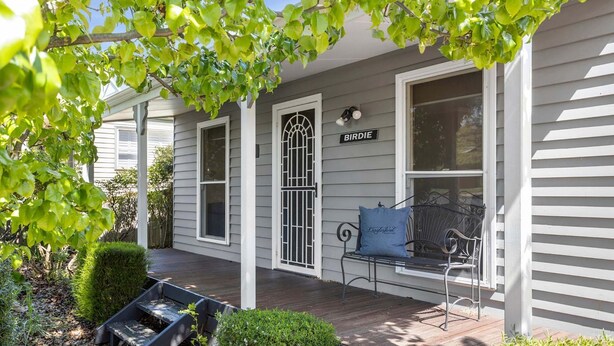 A porch with a bench and a sign that reads "BIRDIE".
