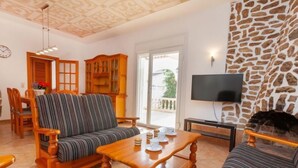 Ein Wohnzimmer mit einer Couch, Sesseln, einem Couchtisch, einem Kamin und einem Fernseher.