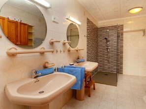 Une salle de bain avec deux lavabos, un miroir et un espace douche.