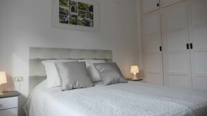 A neatly made bed with a white headboard, two bedside lamps, and a framed photograph above the bed.