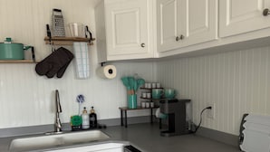 A kitchen with white cabinets, a dishwasher, a sink, and a coffee machine. - Waterfront & 4 minutes from the Gulf of Mexico (Perry)