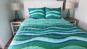 A bed with a striped quilt, two bedside tables with lamps, and a white headboard. - Waterfront & 4 minutes from the Gulf of Mexico (Perry)