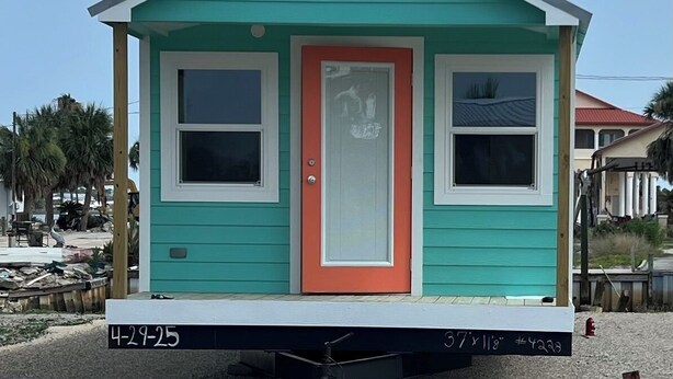 A small, single-story house with a red door and white-framed windows, situated on a gravel surface. - Waterfront & 4 minutes from the Gulf of Mexico (Perry)