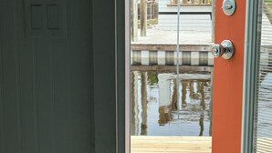 A bedroom with a bed, a door leading to an outdoor deck, and a window with blinds. - Waterfront & 4 minutes from the Gulf of Mexico (Perry)