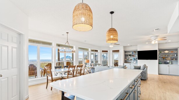 Een ruime keuken met een groot eiland, hangende lampen en uitzicht op de oceaan.