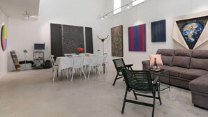 Una galería espaciosa con comedor, arte moderno en las paredes y una zona de estar cómoda con sofá y sillones.