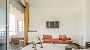 A modern living room with a white sofa, a glass table, and a TV mounted on the wall. - Cosy apartment for 4 people with WIFI, TV and balcony (Tossa De Mar)