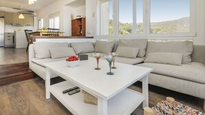 A modern living room with a white sofa, a coffee table, and a view of the kitchen and dining area. - Cosy apartment for 4 people with WIFI, TV and balcony (Tossa De Mar)