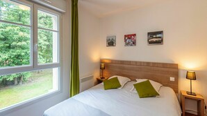 A hotel room with a large bed, two bedside tables, a window with curtains, and three framed pictures on the wall. - Cosy apartment in villa for 6 people with pool, internet, TV, terrace and pets allowed (Marson)