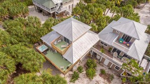 Une propriété de deux étages située en bord de mer, dotée d’un patio couvert, d’un espace salon extérieur et d’une piscine.