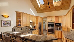 A spacious kitchen with wooden cabinets, granite countertops, and a large island with bar stools.