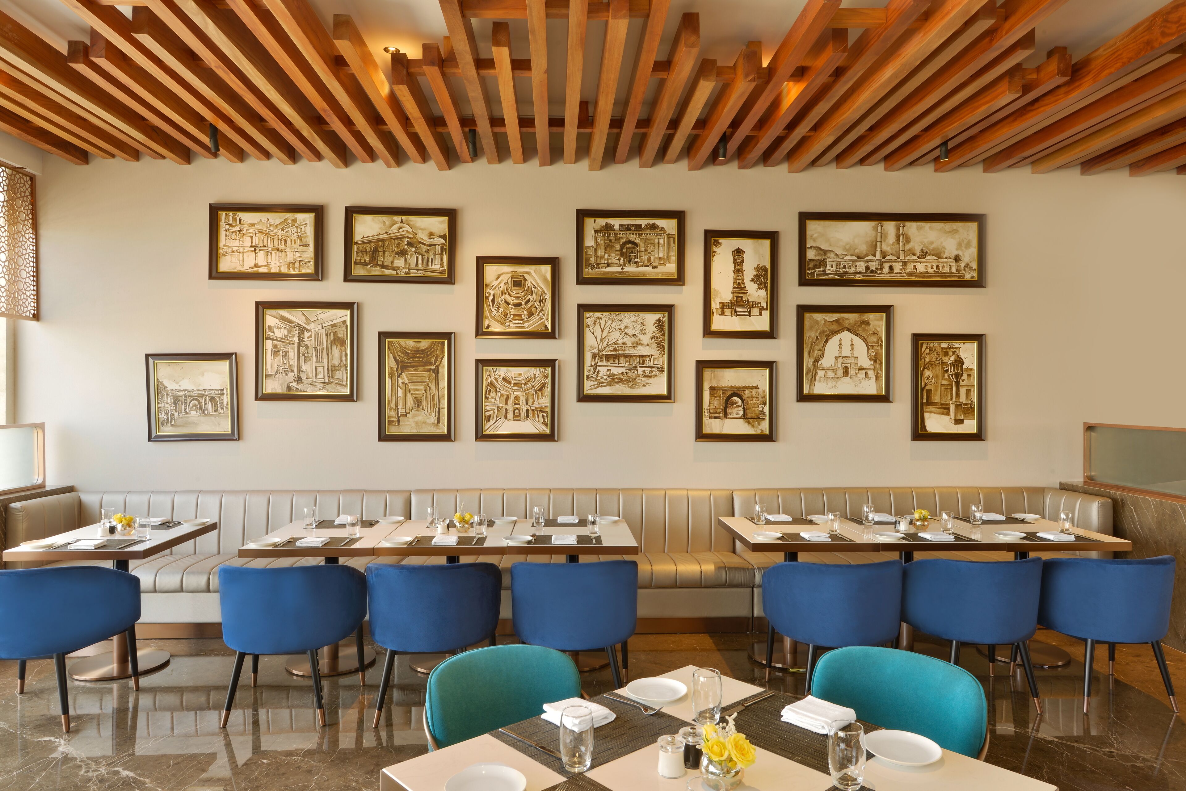Un restaurante con una barra alargada, sillas azules y cuadros enmarcados en la pared.