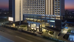A modern hotel with a grid of rooms, a prominent 'TAJ' sign, and a well-lit entrance area.