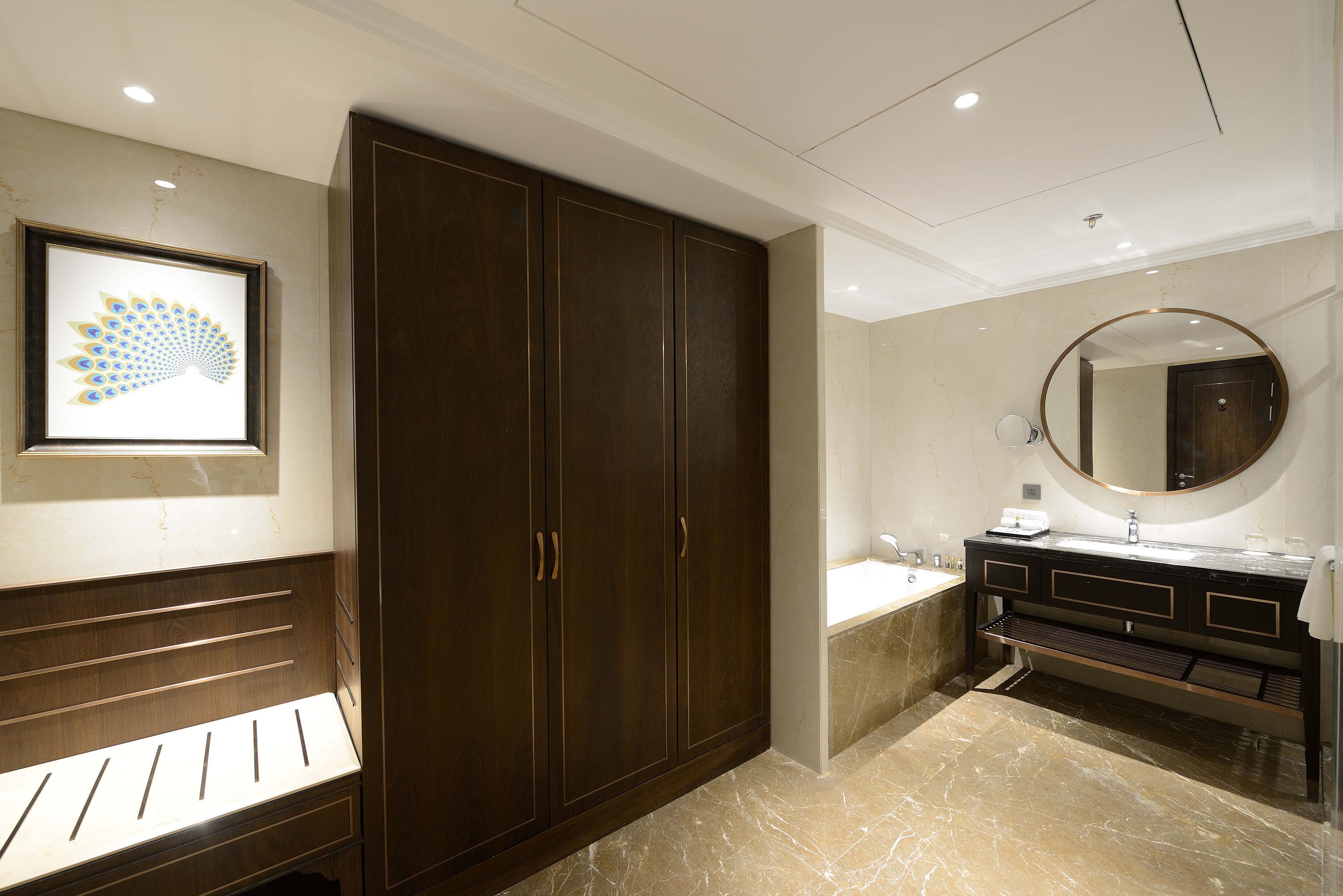 A modern bathroom with a large dark wooden wardrobe, a marble floor, a round mirror, and a sink with a vanity.