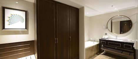 A modern bathroom with a large dark wooden wardrobe, a marble floor, a round mirror, and a sink with a vanity.