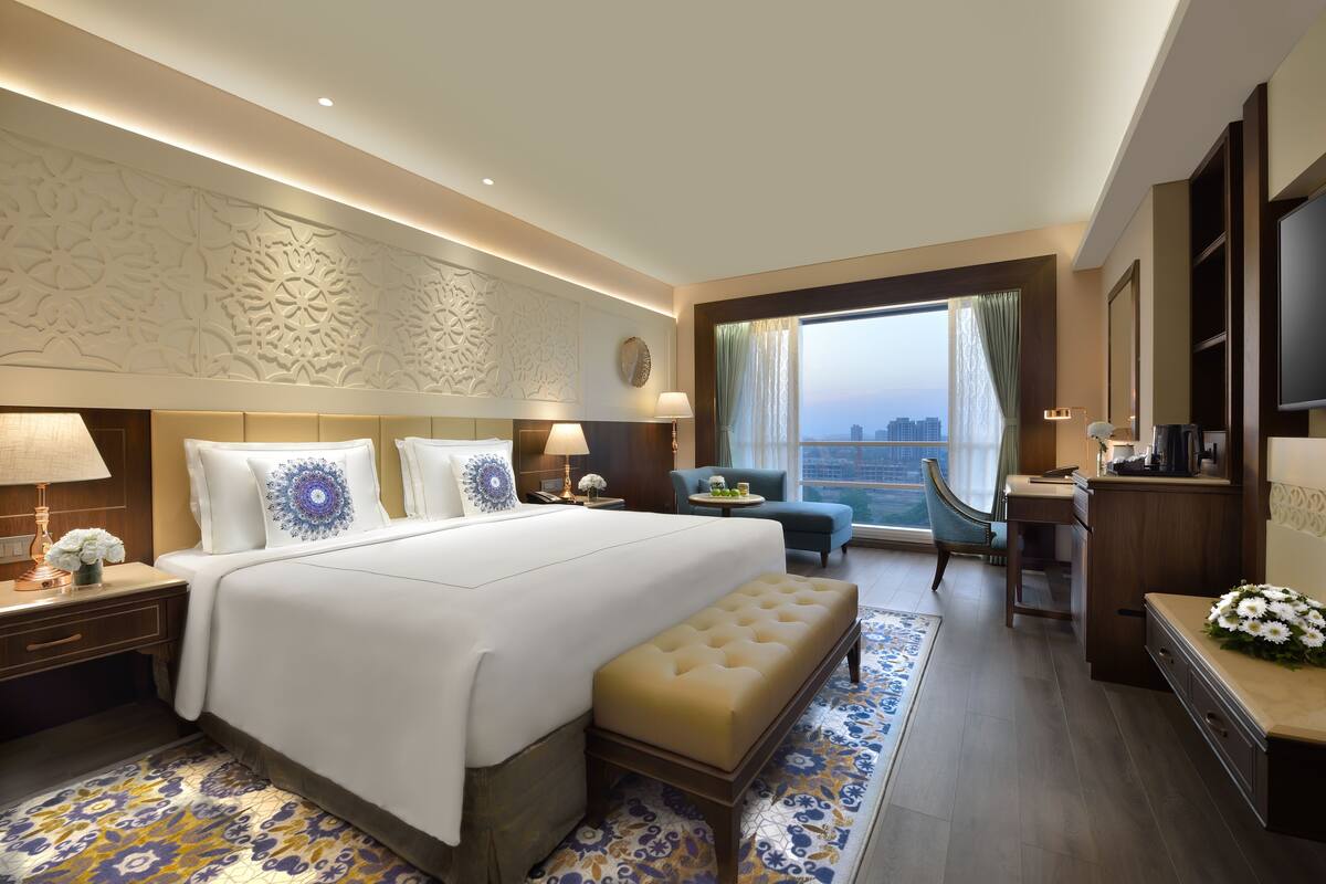 Een hotelkamer met een groot bed, een bureau, een stoel en uitzicht op de stad.