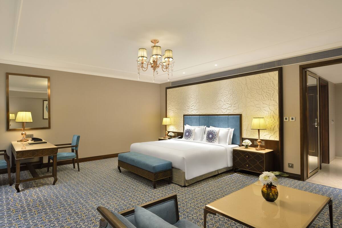 Een hotelkamer met een groot bed, een bureau met stoel, een bijzettafeltje en een decoratieve vaas.