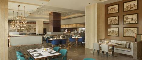Un restaurante espacioso con techos altos, iluminación moderna y diversas opciones de asientos, incluyendo mesas y cabinas.