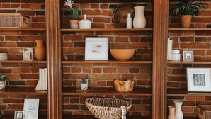 Een bakstenen muur met planken waarop decoratieve objecten staan.