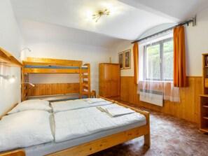 A bunk bed room with a wooden floor, a window with curtains, and a ceiling light fixture. - Malovidy by Interhome (Rataje nad Sázavou)