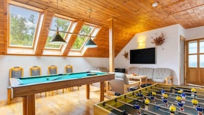 Una habitación acogedora con mesa de billar, mesa de futbolín y un sofá.