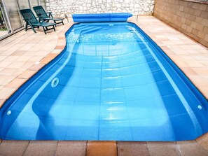 A rectangular swimming pool with a blue interior, surrounded by a stone wall and a tiled patio area. - Malovidy by Interhome (Rataje nad Sázavou)