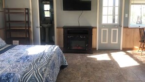 A bedroom with a bed, a fireplace, a television, and a door leading to a bathroom. - Bertucci’s Country Cabin (Williford)