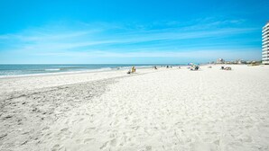 Una amplia playa de arena con cielo azul despejado y océano.