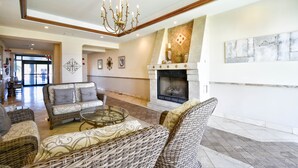 Un amplio salón con muebles de mimbre, chimenea y candelabro.