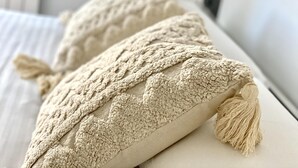 To beige, strukturerede puder med totter på en hvid sofa.
