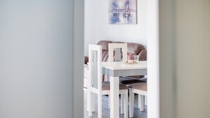 En matplats med ett vitt bord och stolar, en tavla på väggen och en soffa i bakgrunden.