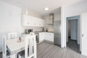 Una cocina moderna con armarios blancos, una mesa de comedor y un microondas integrado.