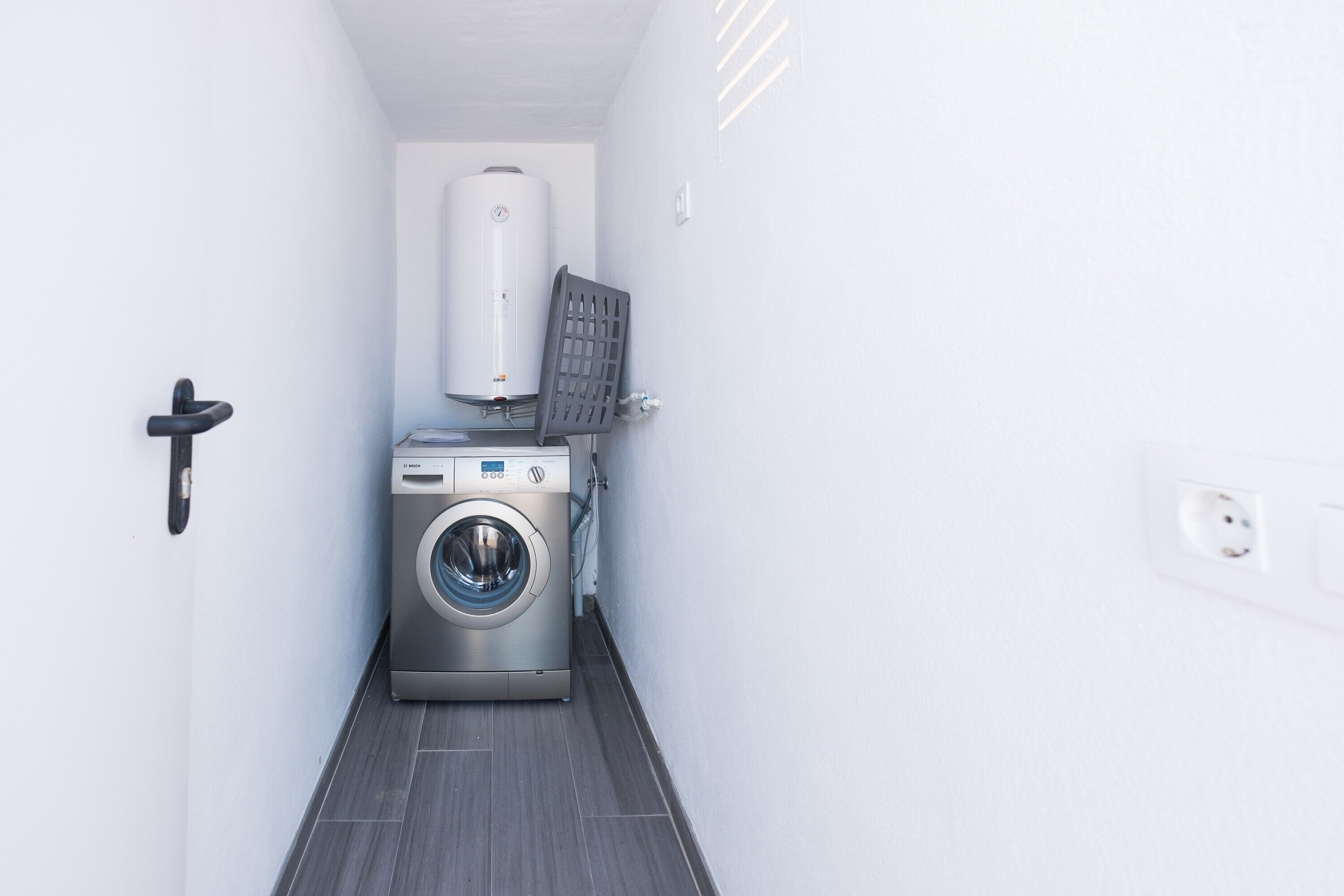 Een kleine wasruimte met een wasmachine, droger en boiler.