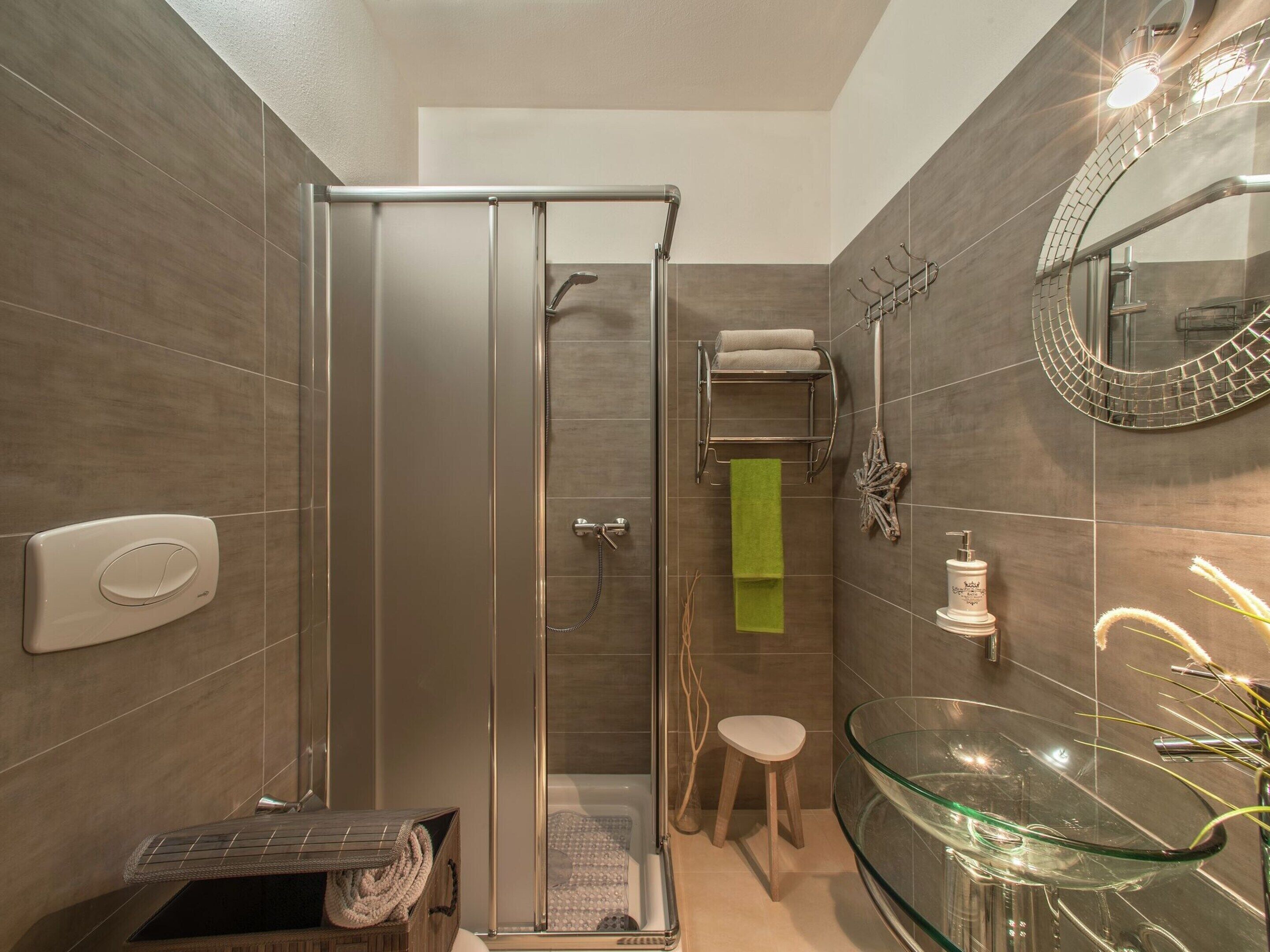 A modern bathroom with a glass shower enclosure, a glass sink, and a towel rack.