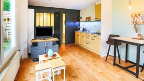 Cocina compacta con televisor, microondas y zona de comedor.
