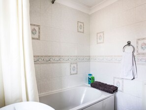 Ein Badezimmer mit einer Badewanne, einem Handtuchhalter mit einem weißen Handtuch und dekorativen Fliesen an den Wänden.