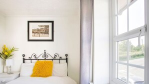 A bedroom with a bed, a framed picture on the wall, a window with a view of the outside, and a nightstand with a lamp and flowers. - Rustic Holiday Home in Birmingham near Motorcycle Museum (Birmingham)