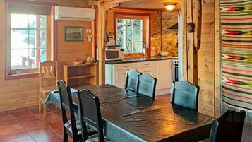 A wooden interior with a dining table, chairs, a kitchen area, and a patterned wall.