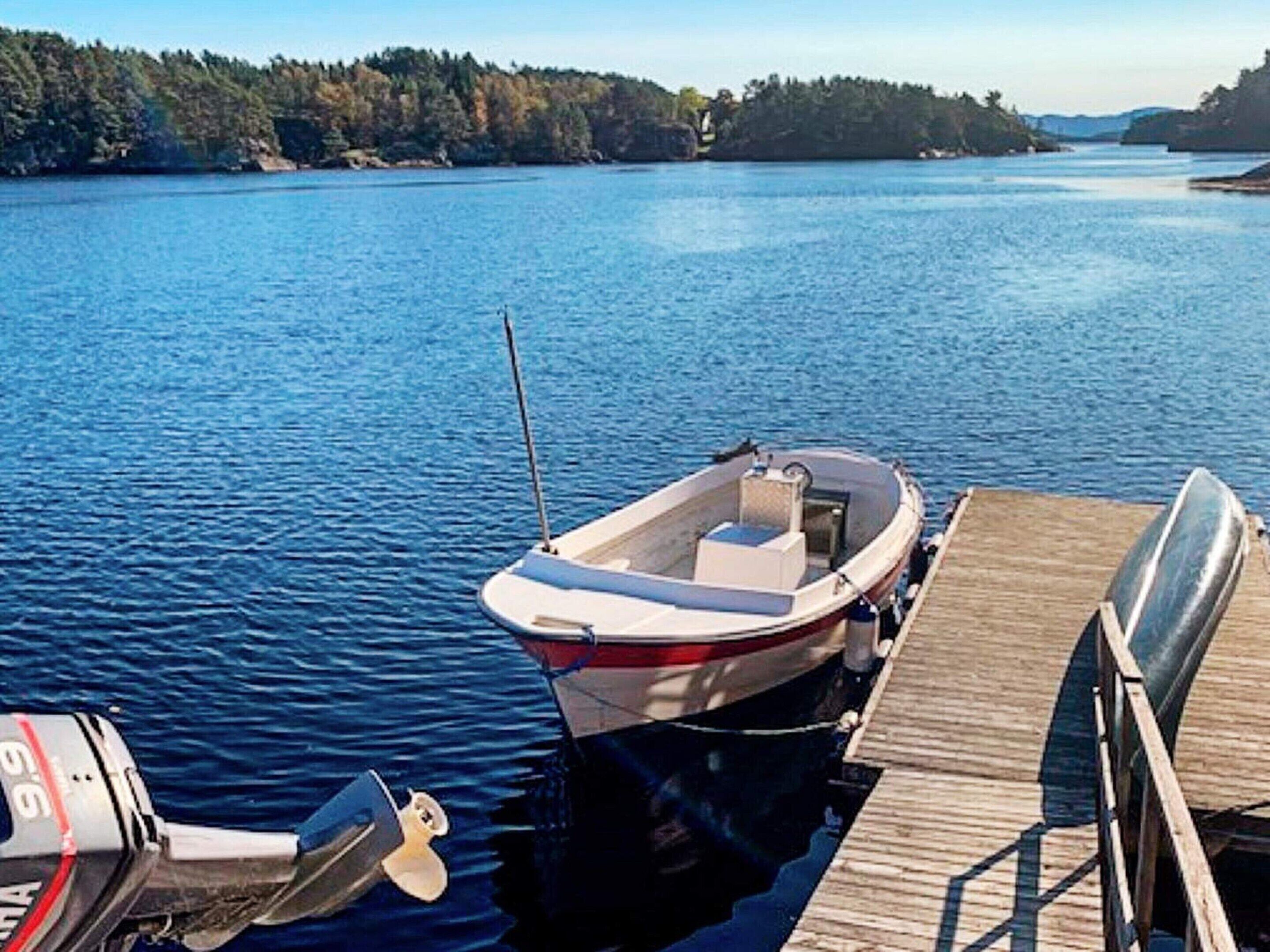 A small motorboat docked at a wooden pier with a motor attached to the side.
