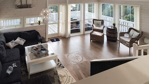 A spacious living room with a high ceiling, large windows, a wooden deck, and a cozy seating area with a sofa and two chairs. - 6 Person Holiday Home in Hartbakke (Solund)